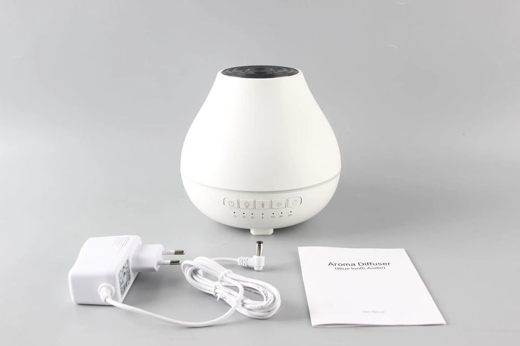 White round Bluetooth humidifier and essential oil diffuser with LED night light on a wooden surface.