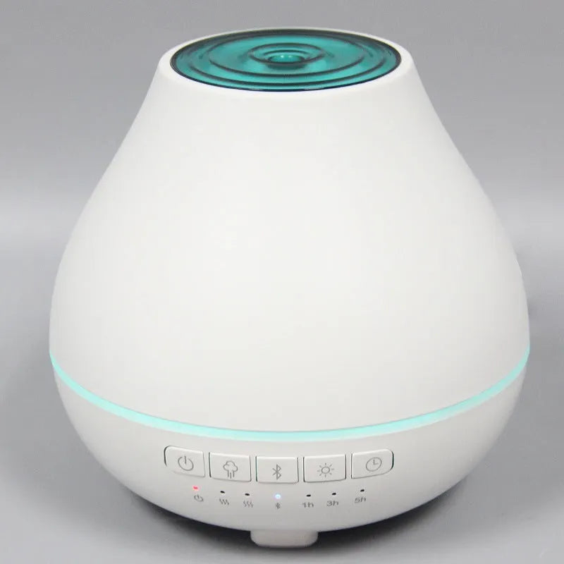 White round Bluetooth humidifier and essential oil diffuser with LED night light on a wooden surface.