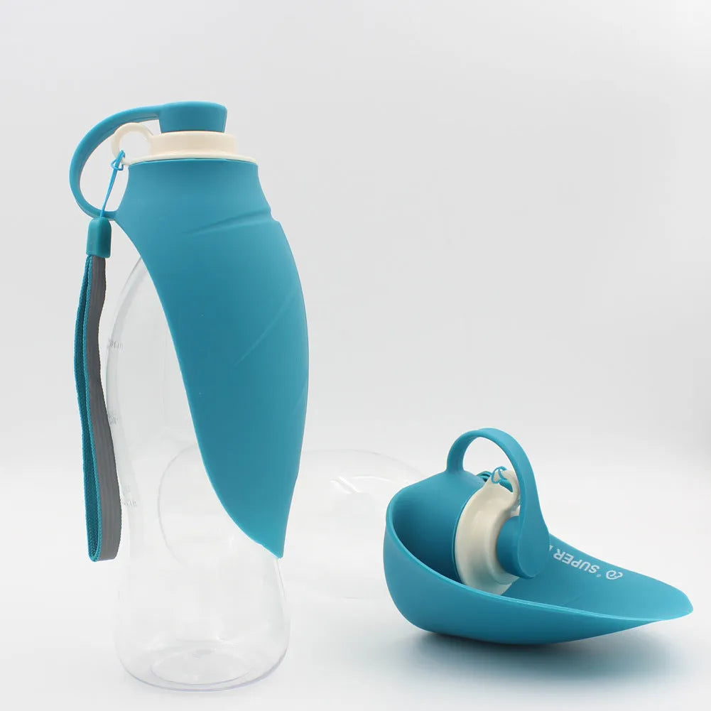 Portable pet water dispenser with black body and flip-up silicone cup next to a dog