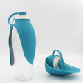 Portable pet water dispenser with black body and flip-up silicone cup next to a dog