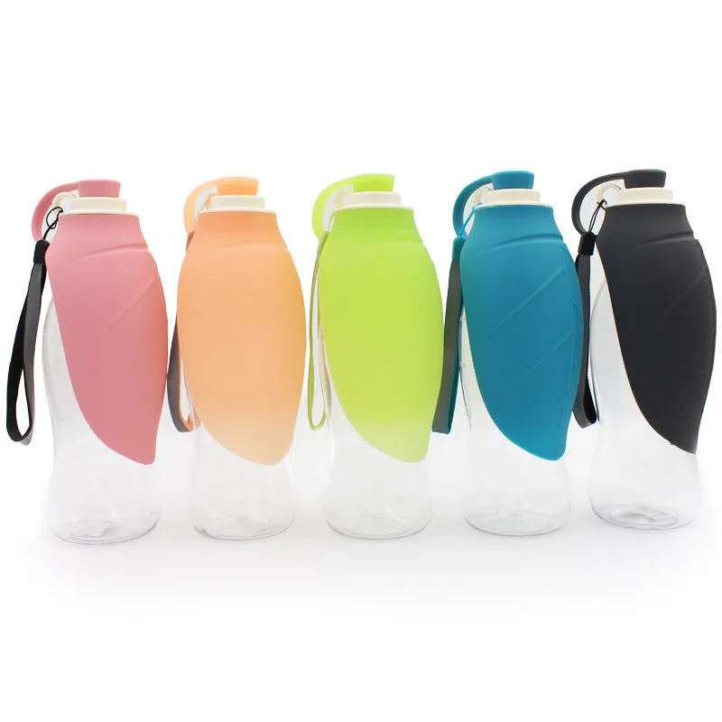 Portable pet water dispenser with black body and flip-up silicone cup next to a dog