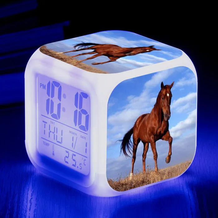 Small square cartoon LED alarm clock with colour-changing face showing digital time and temperature.