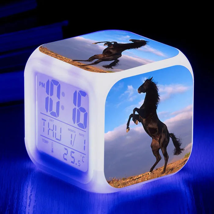 Small square cartoon LED alarm clock with colour-changing face showing digital time and temperature.