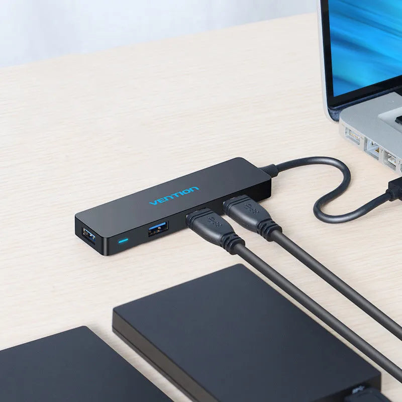 Black four-port USB 3.0 hub with a short connected cable on a desk