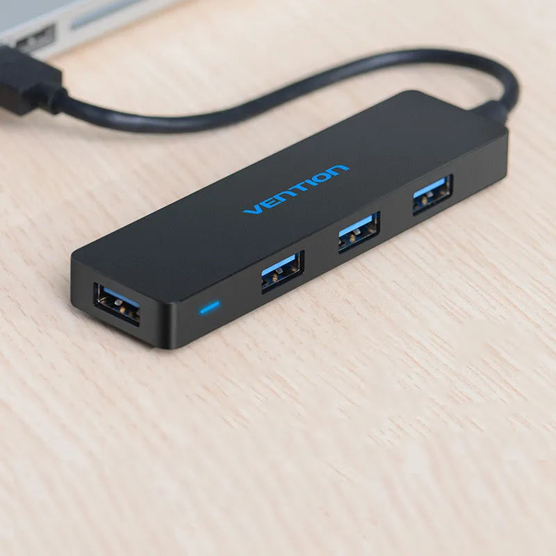 Black four-port USB 3.0 hub with a short connected cable on a desk