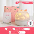 Rechargeable rotating star projector light projecting coloured celestial patterns on wall
