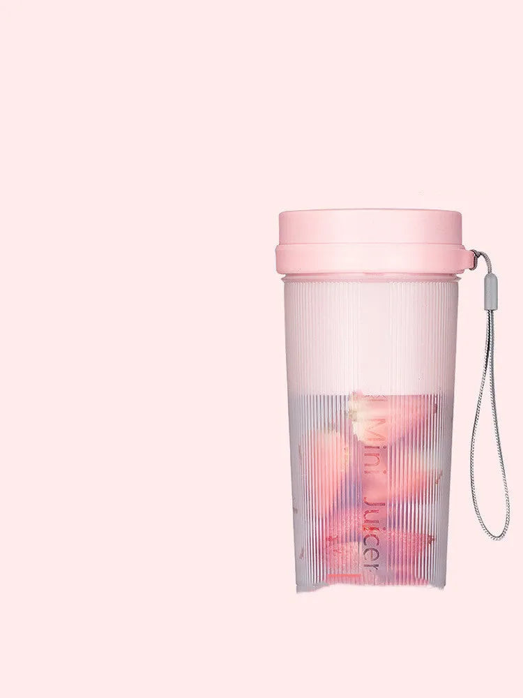 Portable pink and green rechargeable electric juicer cup with USB charging cable.