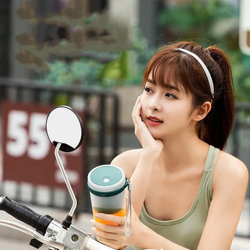 Portable pink and green rechargeable electric juicer cup with USB charging cable.