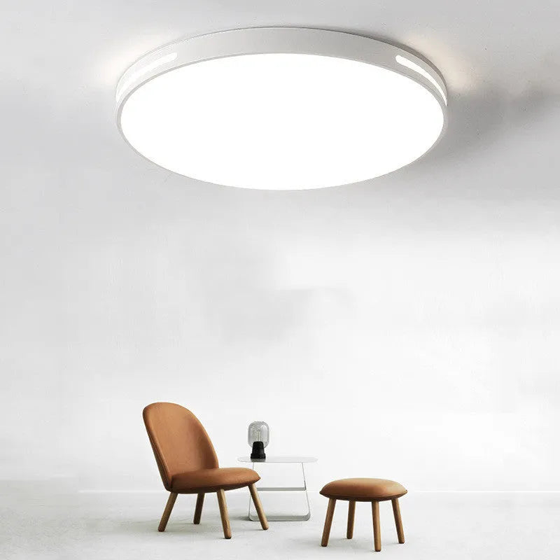 Round white acrylic remote control LED ceiling lamp mounted on a bedroom ceiling.