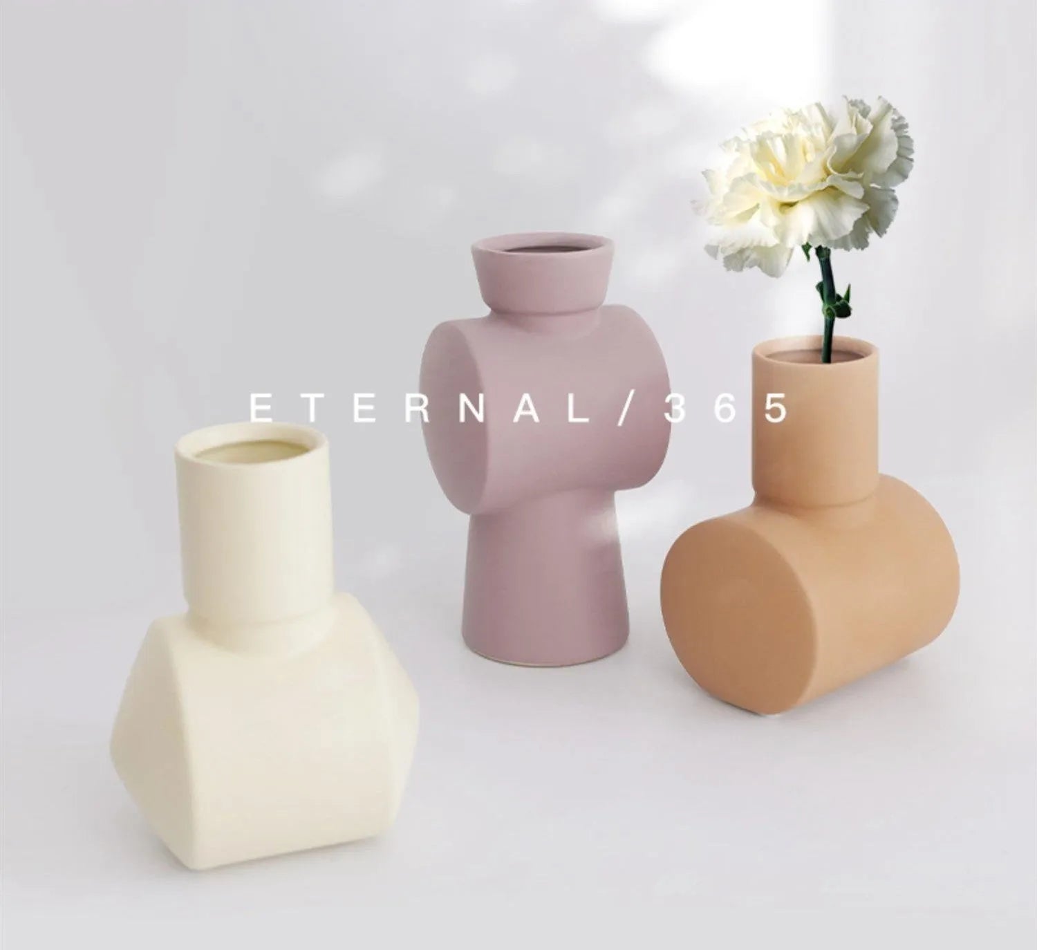 Morandi coloured ceramic vase with hammered glaze texture on a wooden shelf.