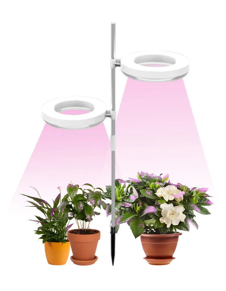 Compact white LED plant growth lamp with adjustable heads on a wooden desk next to a green houseplant.