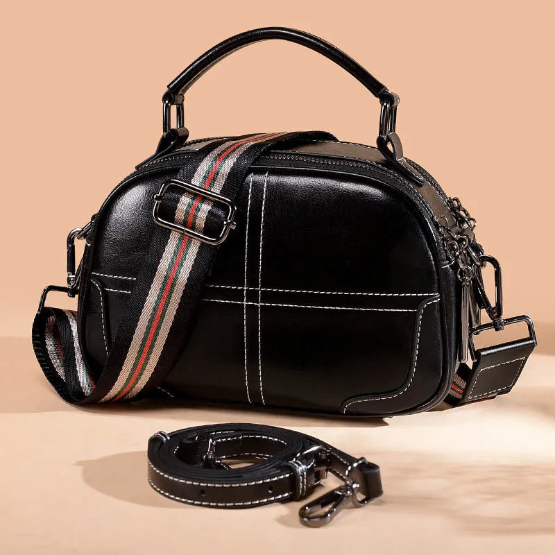Round brown leather handbag with soft handle and zipper opening.