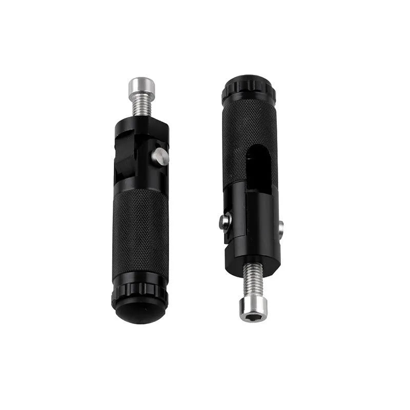 Two black aluminium alloy round folding motorcycle foot pedals on a workbench