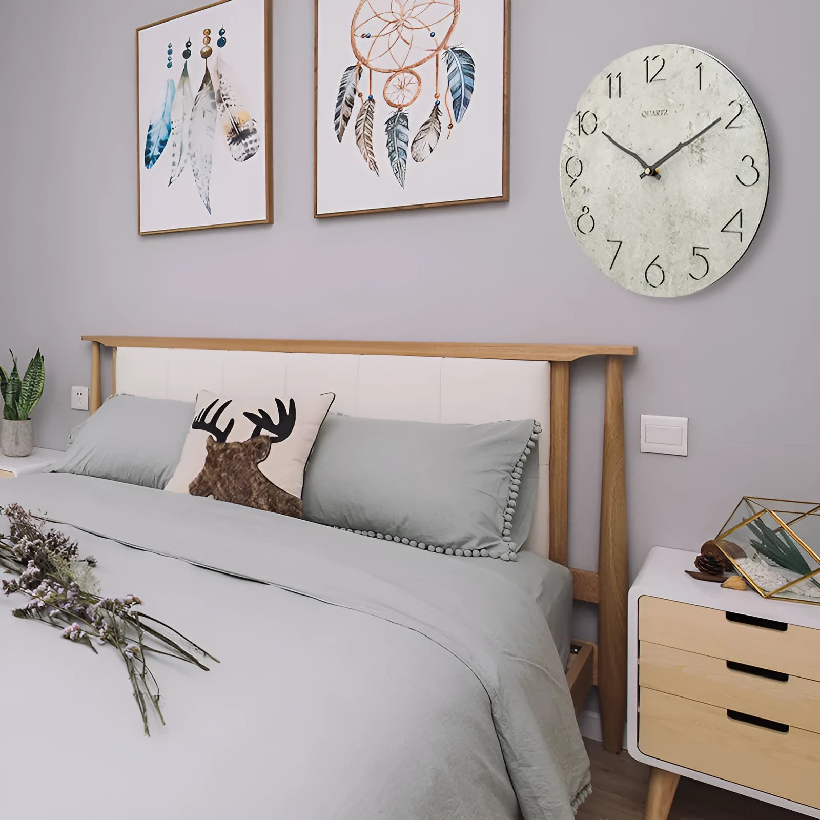 Modern grey European-style wall clock with a round face on a white wall.