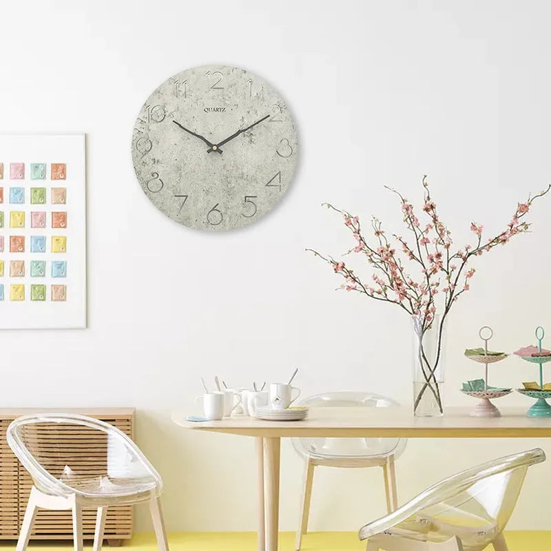 Modern grey European-style wall clock with a round face on a white wall.