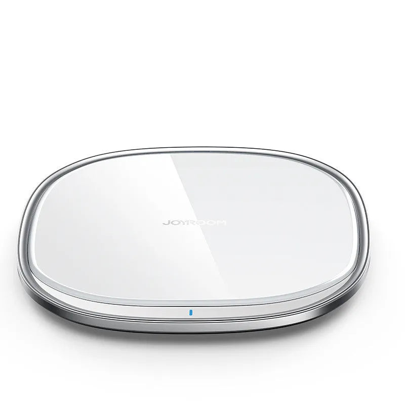 Black square 15W wireless charging pad with glass top on a wooden desk next to a smartphone.