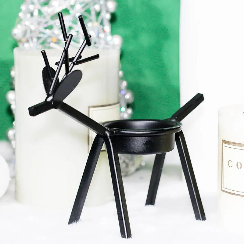 Black iron Christmas deer candlestick holder with elk silhouette on a table.
