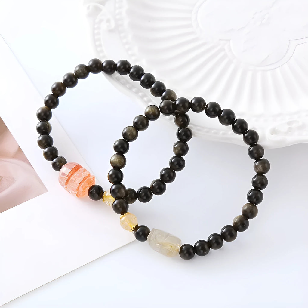 Handmade black obsidian and gold Pi Xiu charm bracelet with red flowers.