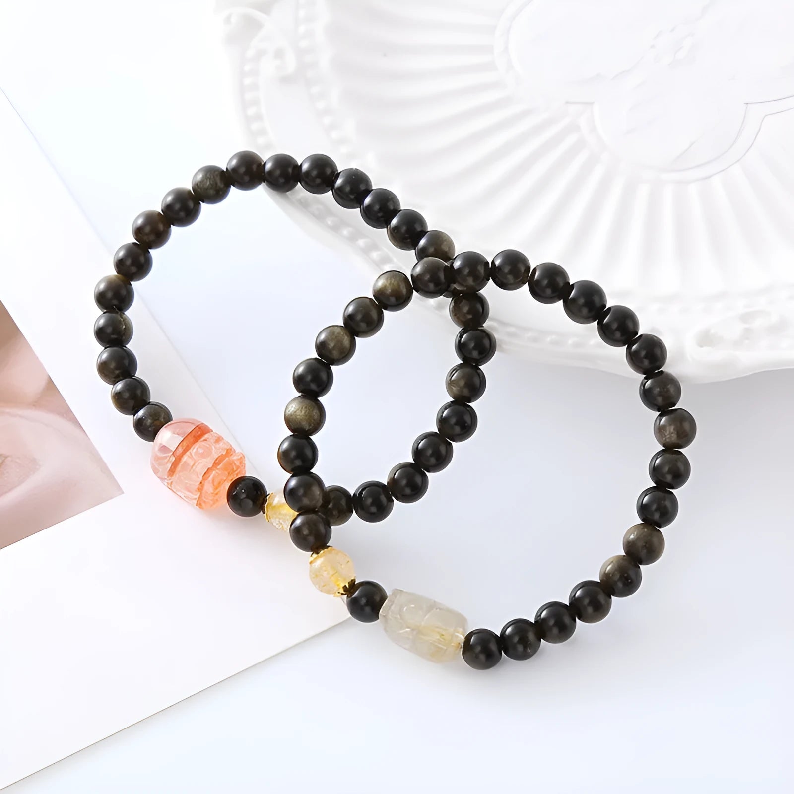 Handmade black obsidian and gold Pi Xiu charm bracelet with red flowers.