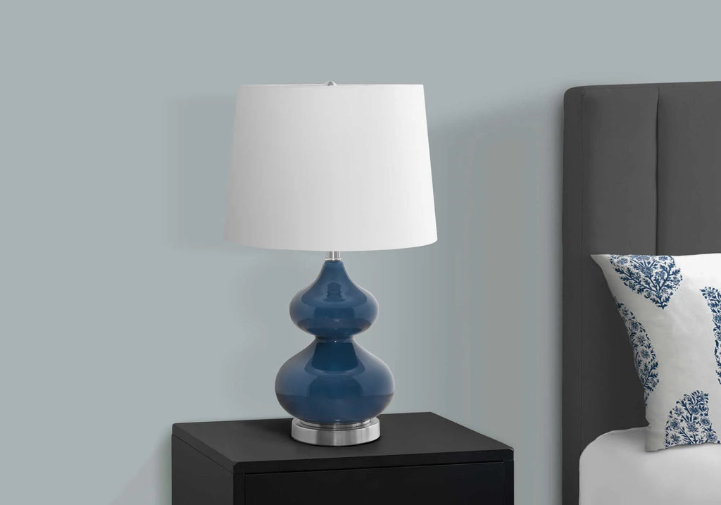 Tall crystal glass desk lamp with a blue cloth shade on a wooden desk.