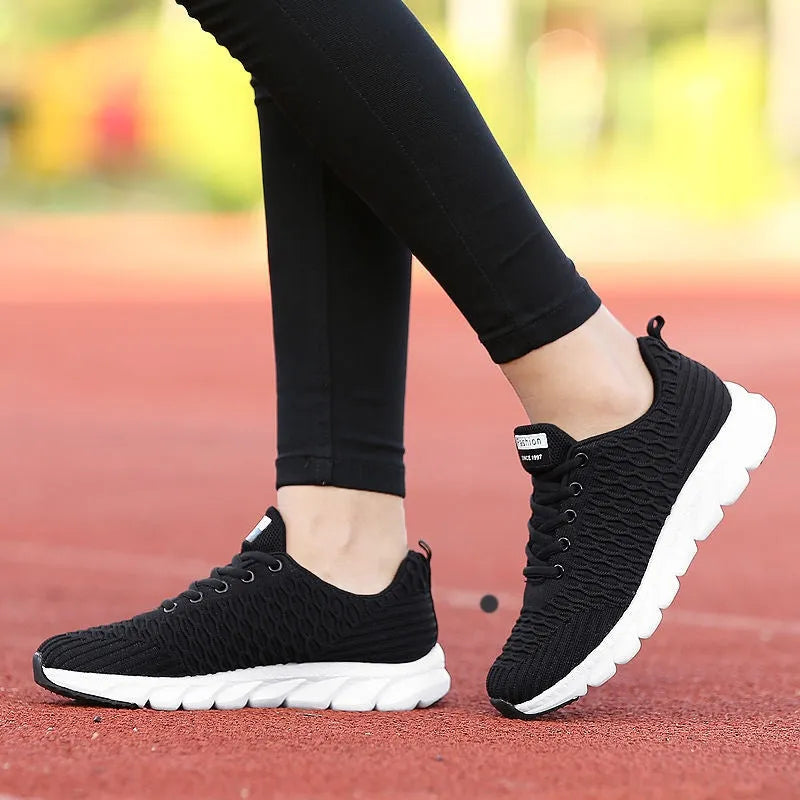 Women's running shoes in black, pink, or white with fly weaving upper and wear-resistant outsole.