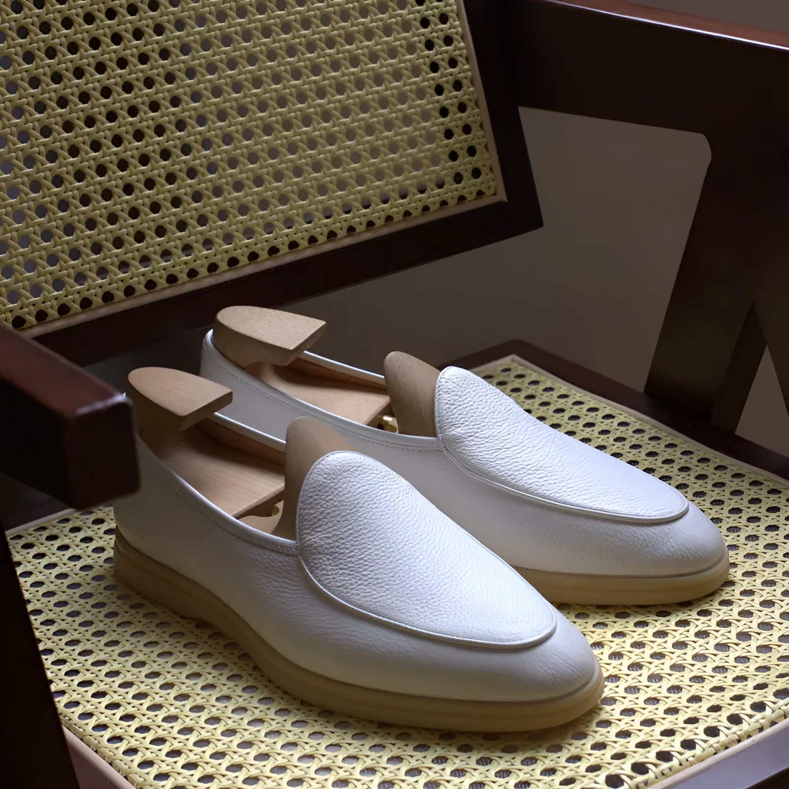 British handmade brown leather men's loafers with a flat TPR sole on a wooden surface.