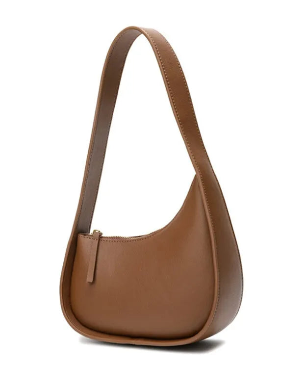 Small half moon shaped leather women's shoulder bag with a wide strap, shown in light brown.
