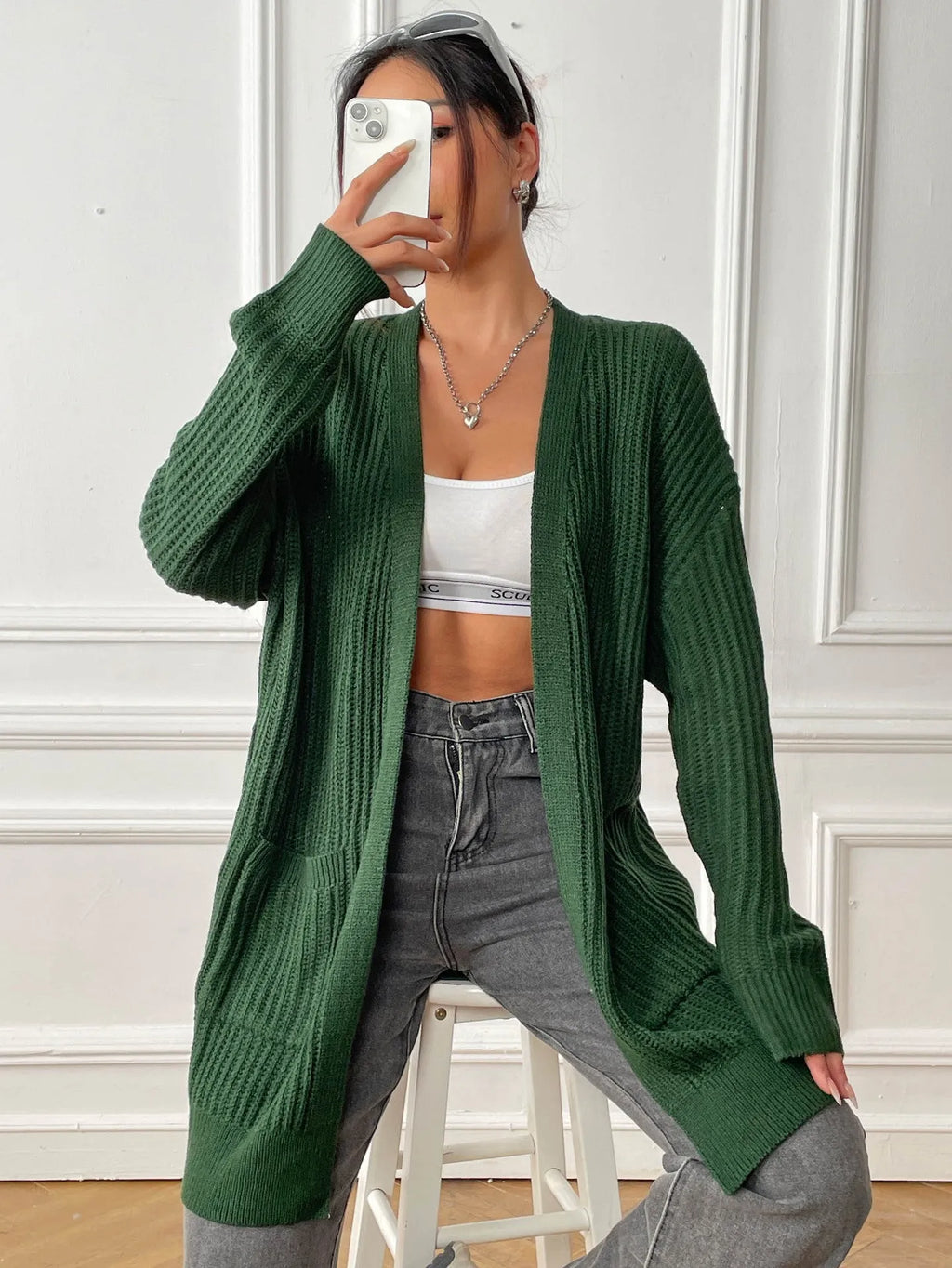 Women's dark green loose cardigan with two front pockets and long sleeves.