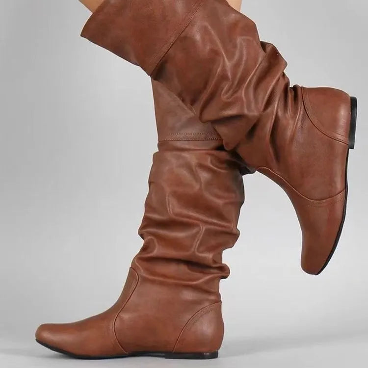 Women's black flat slip-on ankle boots with round toe and high cylinder cut, showing rubber sole.