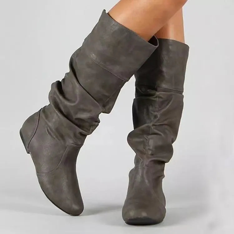 Women's black flat slip-on ankle boots with round toe and high cylinder cut, showing rubber sole.