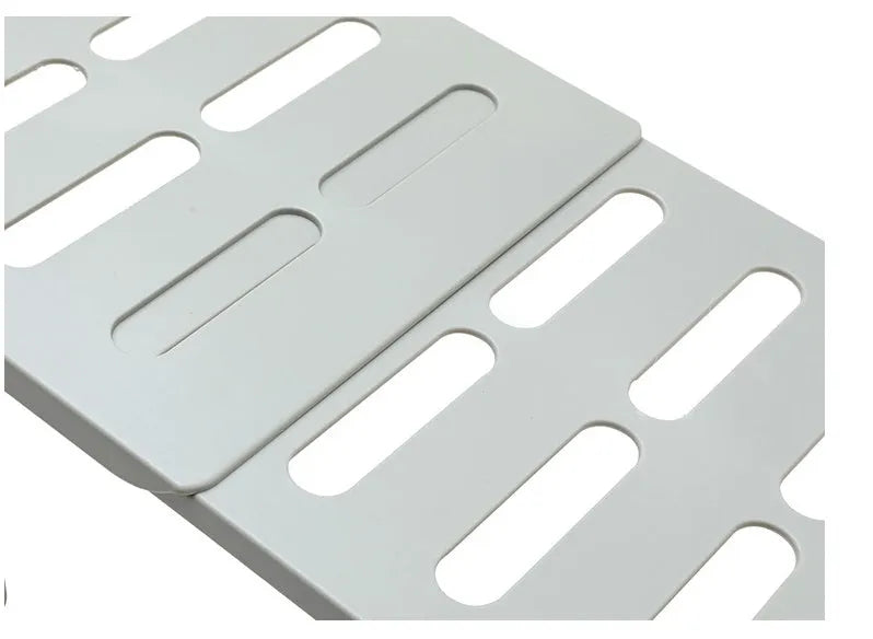 White telescopic plastic kitchen rack with single shelf, shown at adjusted height on a kitchen floor.