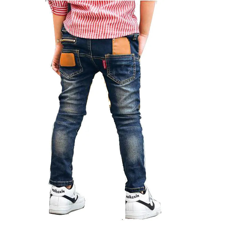 Boy wearing dark blue stretch denim jeans with zipper pockets, size chart shown