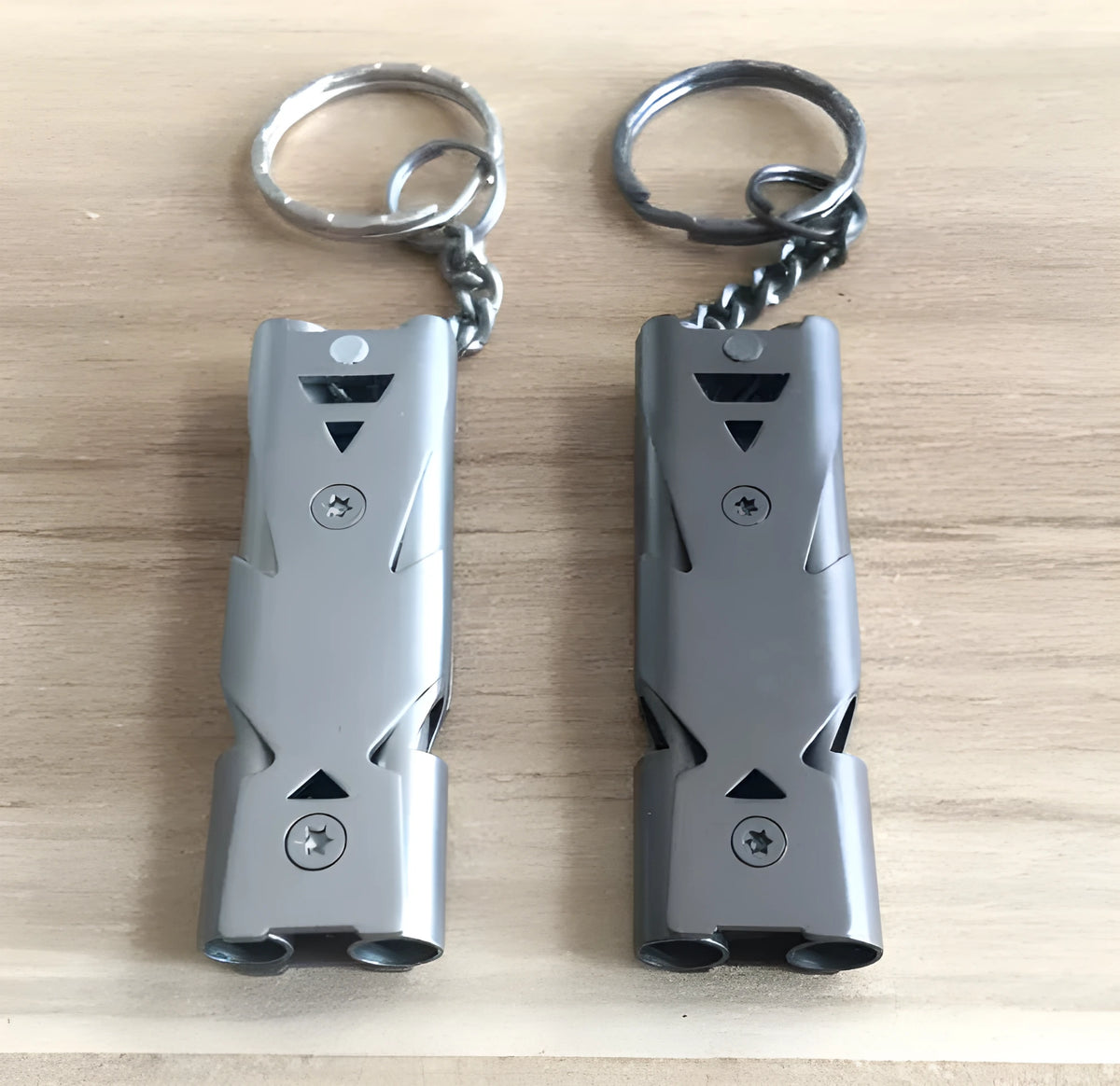 Compact metal keychain whistle with black lanyard on a keyring for outdoor emergency use