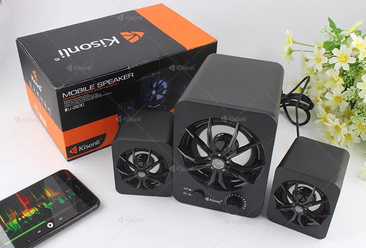 Green 2.1 USB computer speaker with LED lights on a desk next to a laptop.
