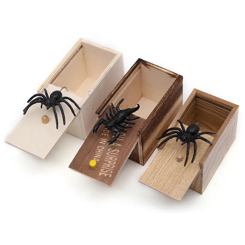 Wooden prank scare box with a lifelike spider figurine on a table.