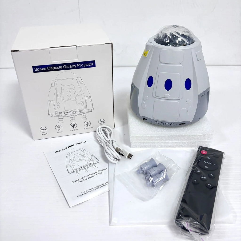 Space capsule shaped USB galaxy projection lamp with remote control on a desk.