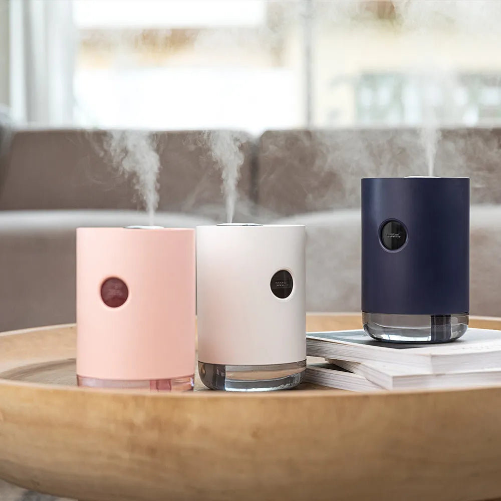 Blue wireless USB humidifier with water tank on a wooden desk next to a plant.