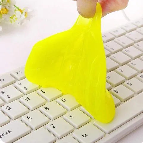 Blue and yellow lumps of Magic Cleaning Gel adhesive putty for dust removal, shown with a car vent and keyboard.