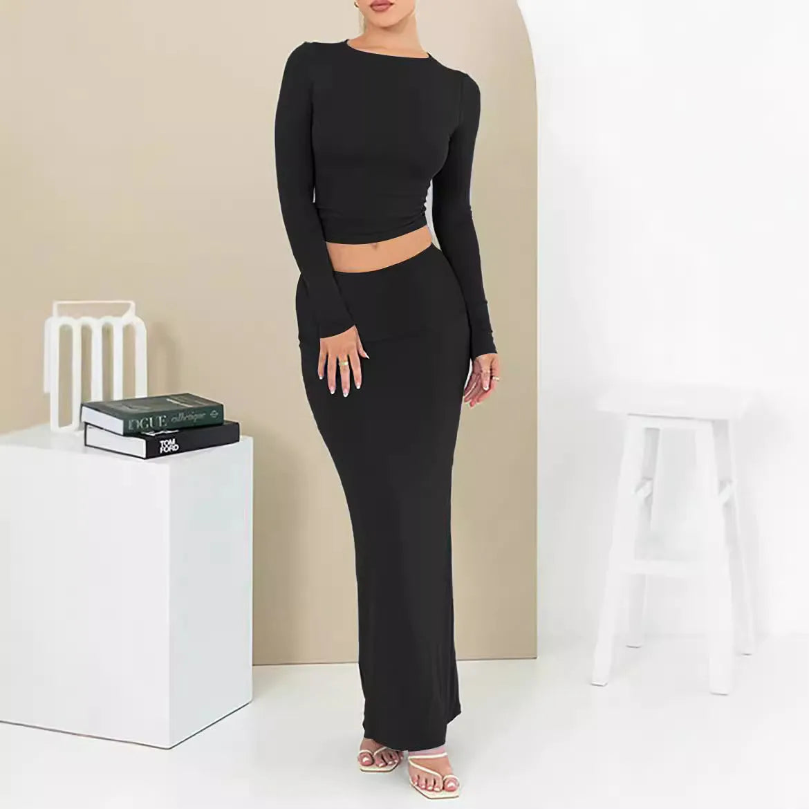 Women's black slim fit two-piece suit with exposed navel top and long skirt.