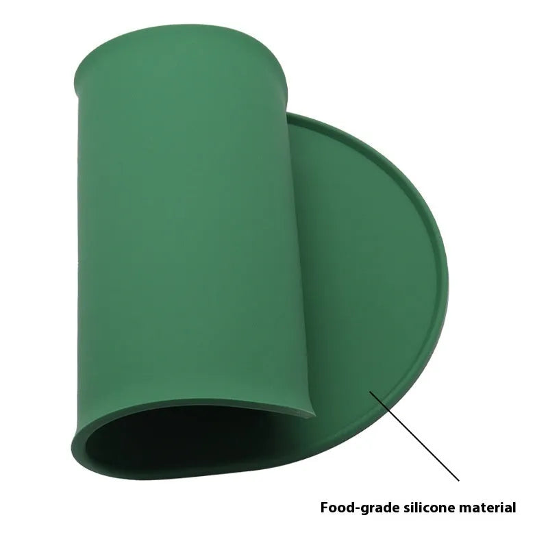 Beige silicone cat feeding mat with raised edges holding a food and water bowl on a wooden floor.