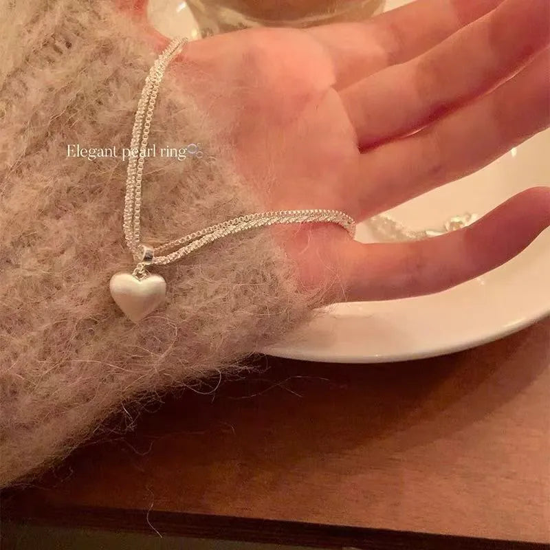 Brushed double-layer heart pendant necklace with adjustable chain on white background