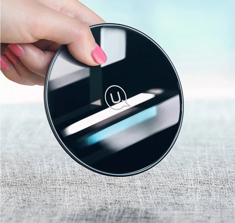 Black glass disc wireless charger with LED indicator light on smooth surface