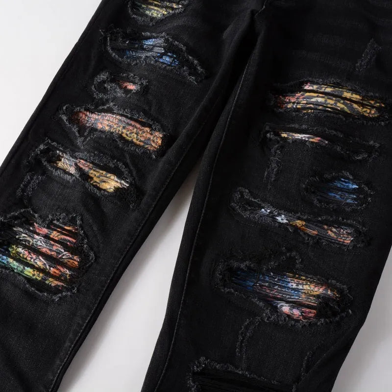 Men's black tattered stretch denim jeans with printed patch on a white background, front view