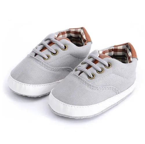 Solid colour baby canvas shoes with a front strap, shown in light grey on a white background.