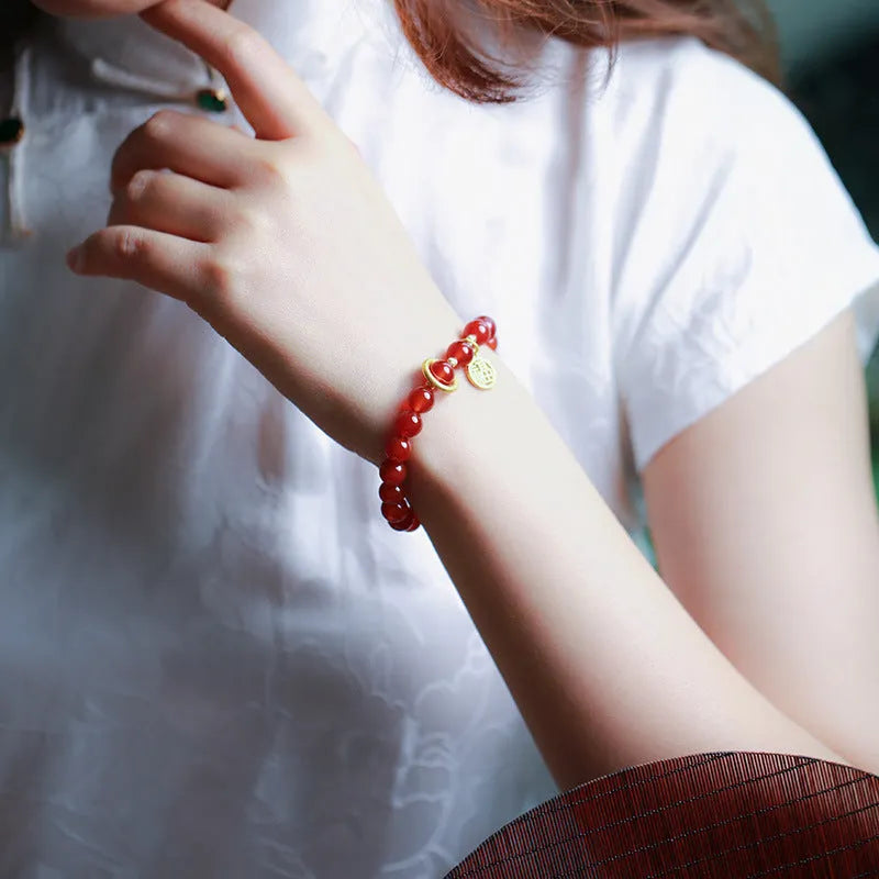 Close-up of a red agate beaded bracelet with woven design and a paper blessing card.