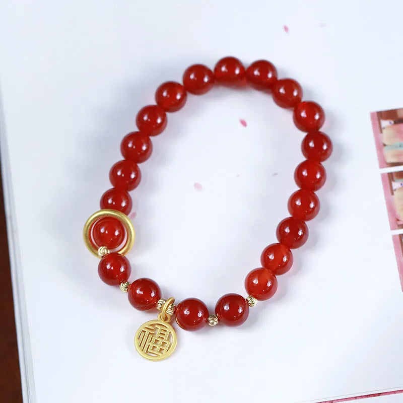 Close-up of a red agate beaded bracelet with woven design and a paper blessing card.