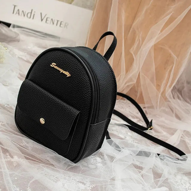 Compact black PU leather women's shoulder backpack worn crossbody, showing zipper closure and simple design.