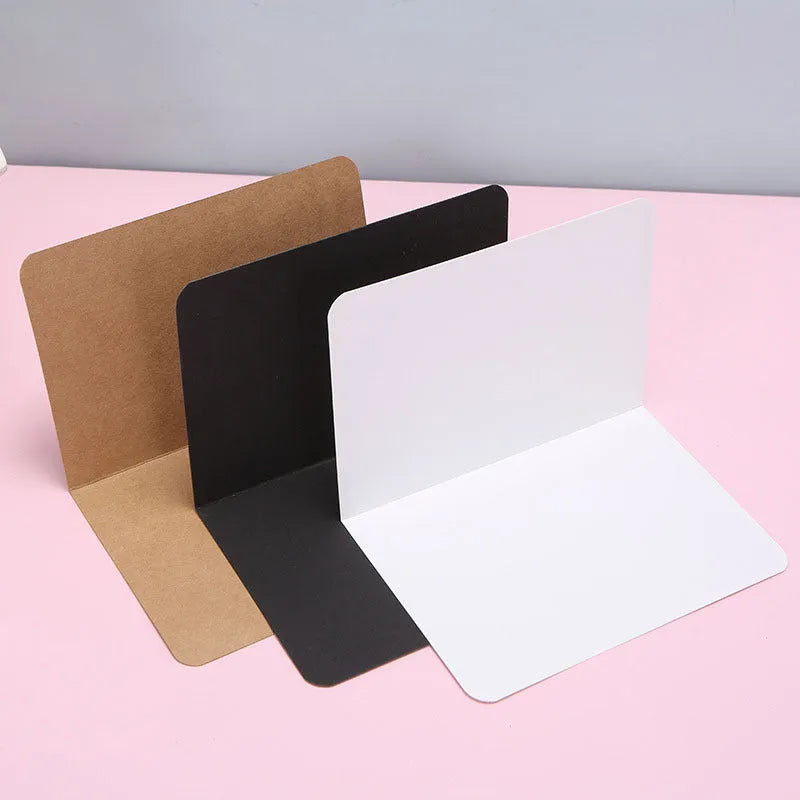 Pack of 100 folded kraft paper greeting cards in 10x15cm size, showing black, brown, and white colour options.