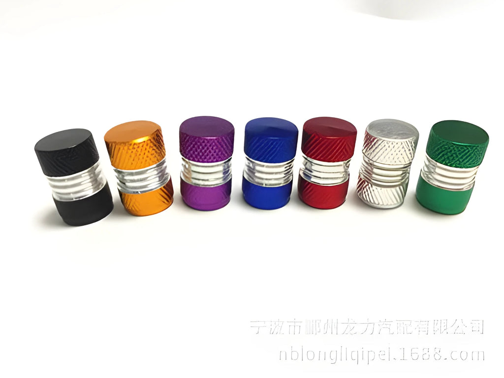 Seven aluminium alloy tyre valve dust caps in black, blue, gold, green, purple, red, and silver on a white background