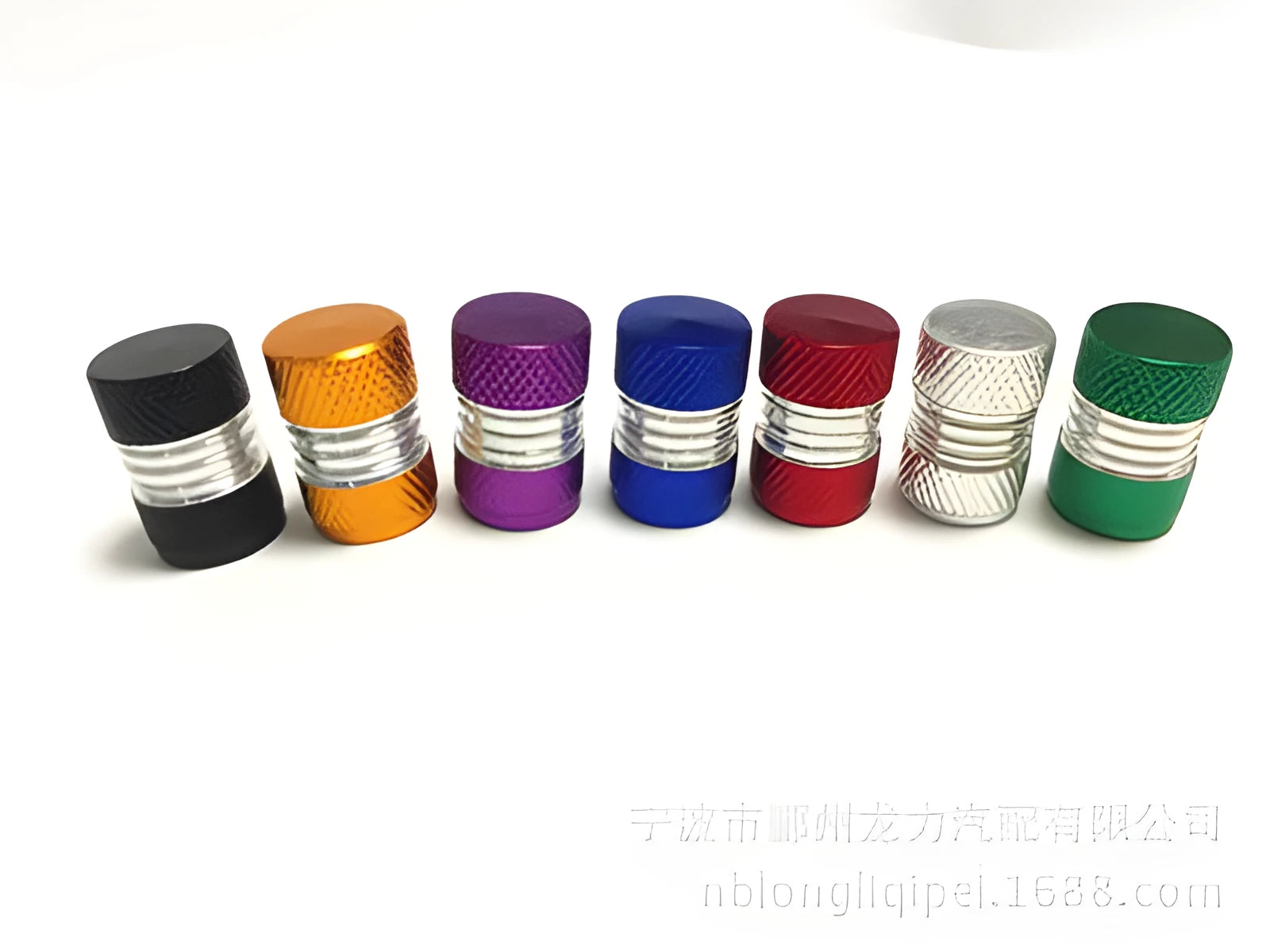 Seven aluminium alloy tyre valve dust caps in black, blue, gold, green, purple, red, and silver on a white background